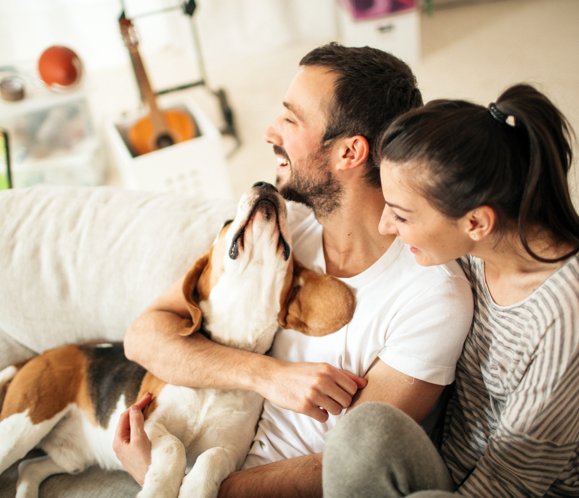 Young couple hugging their dog on their couch