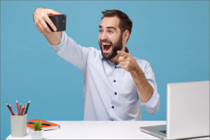 Man taking selfie at desk with laptop