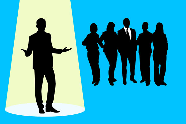 Silhouette of recruitment candidate in the spotlight with other candidates looking on.