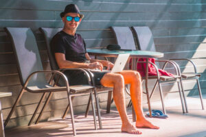 Man on his laptop by a pool